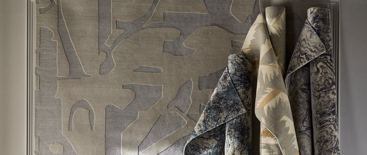 Various rolls of rugs stood up vertically against neutral tone rug backdrop